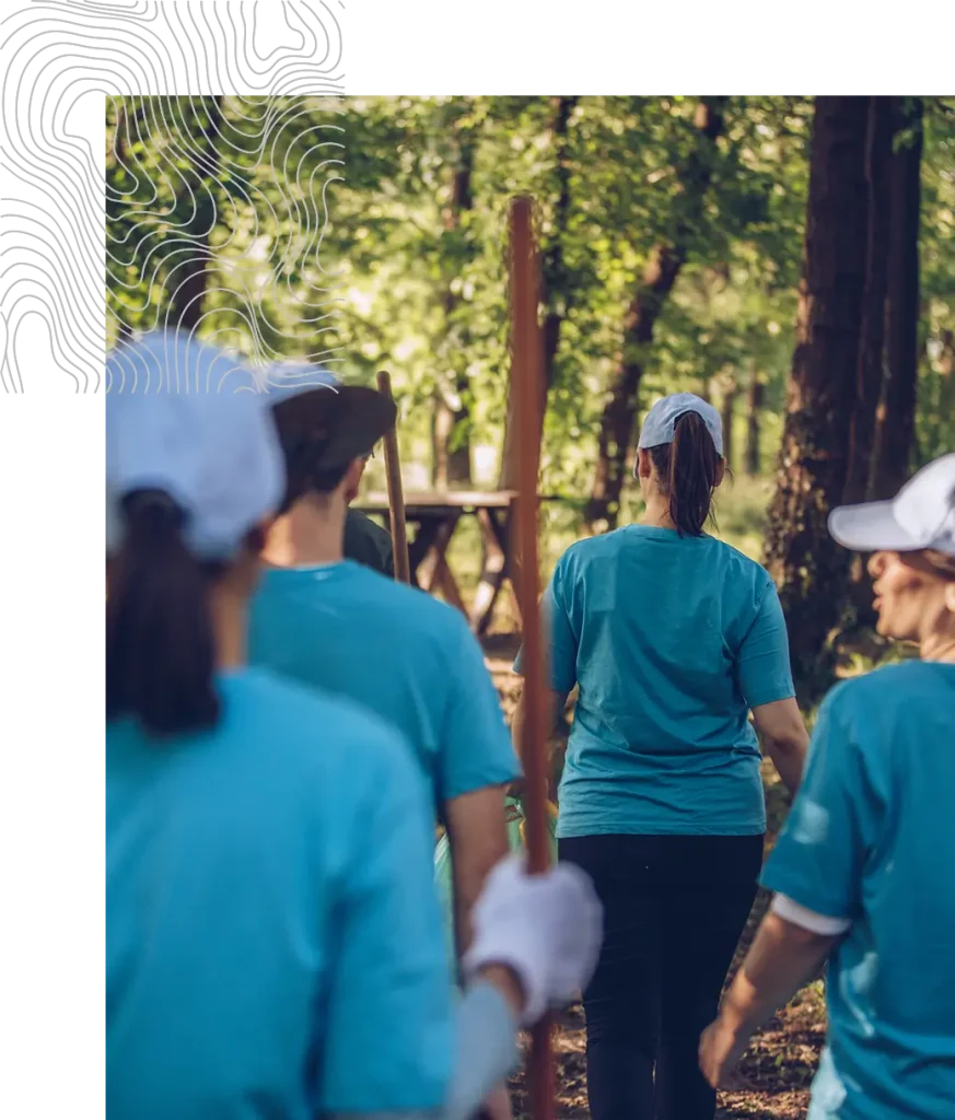 Group of volunteers in blue shirts working in a forest.