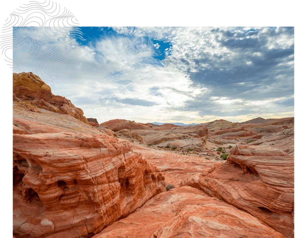 Red rock formations under a cloudy sky in a desert landscape.